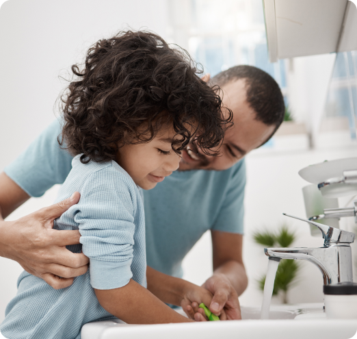 Man helping small girl wash hands.